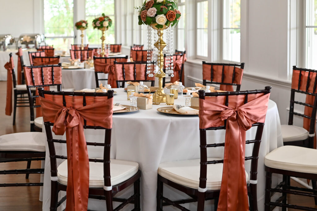 Dusty rose colored wedding reception decor.  Topiary table centerpieces with rose, gold and ivory flowers.  Golf course wedding venue reception decor.