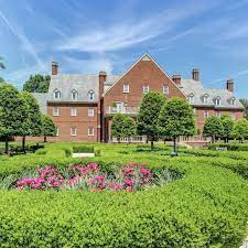 Photo of a historic brick building in Virginia Beach. Lush grounds surrounding the building with greens and florals. Beautiful sky above the building.