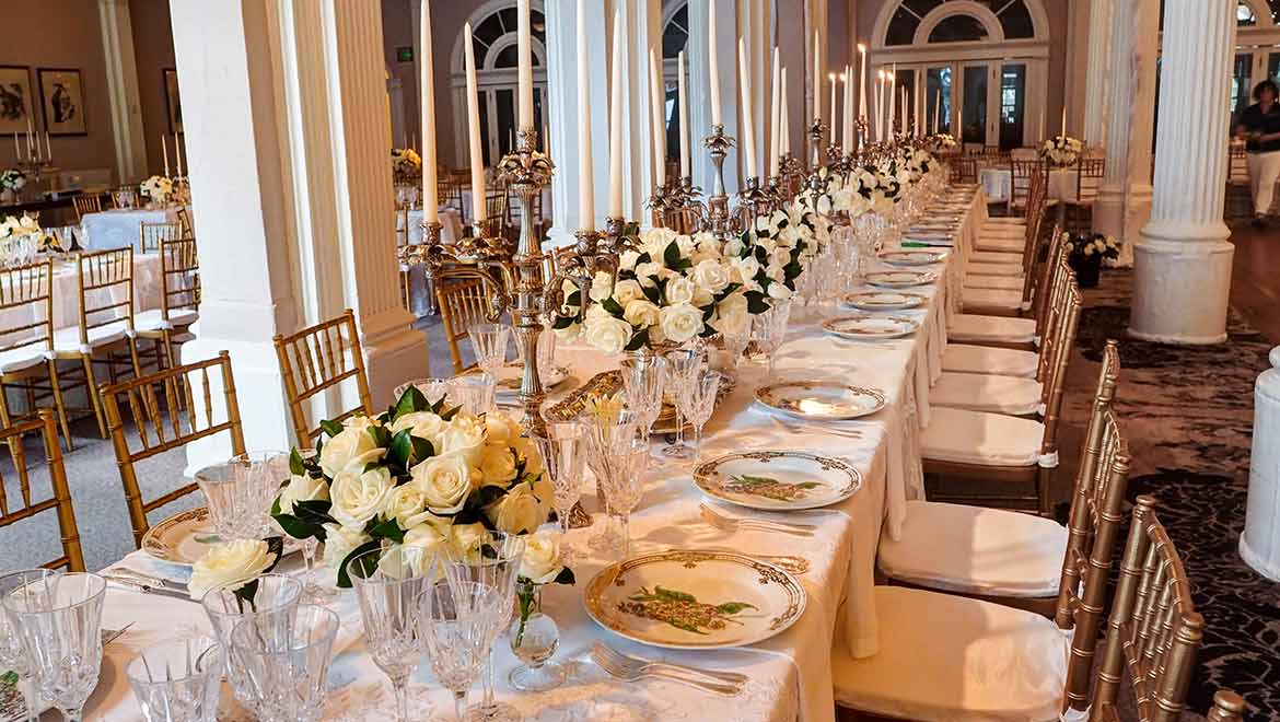 Dedacent wedding decor with white florals on a large table with wedding linens. Hotel ballroom table setting