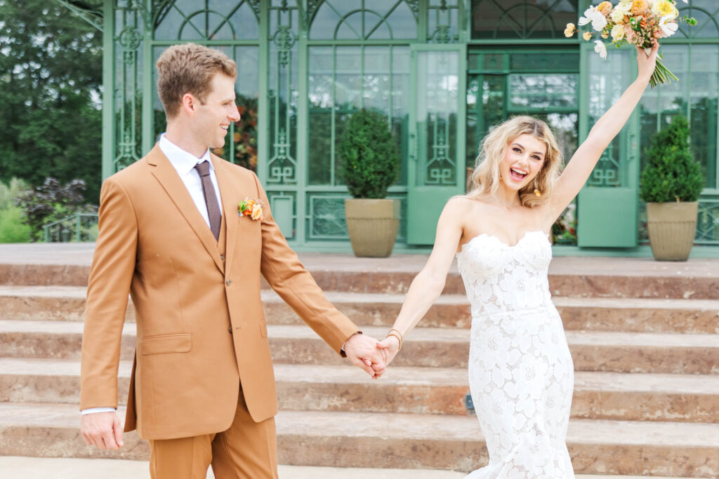 Bride and Groom celebrating coming out of ceremony space.  Groom looking and laughing at the Bride as she has a huge smile and is waving her bouquet in the air to celebrate. Photographed by a Virginia Wedding Photographer