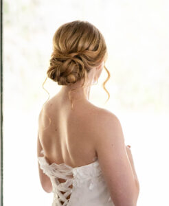 Photo of a Bride with strawberry blonde hair in a low updo.  A few tendrils falling down.  Bride has a strapless dress with wide ribbons like a corset.  Taken by a Virginia Wedding Photographer