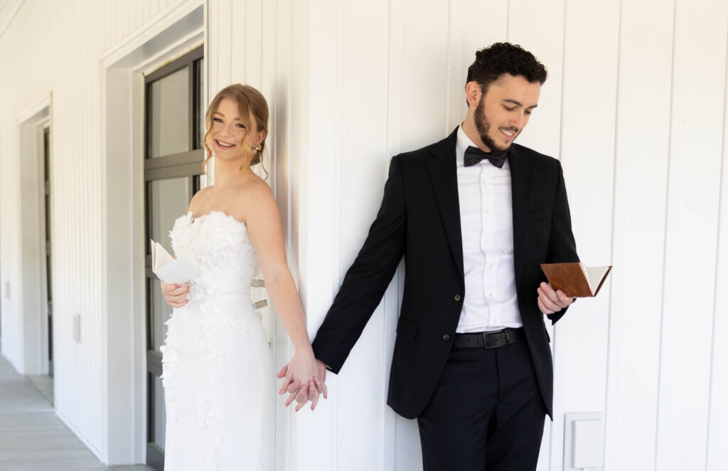 Bride and Groom holding hands but on opposite side of the wall so they do not see each other.  They are reading their vows.  