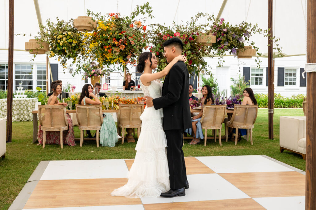 Bride and Groom dancing on a tan and white checkerboard dance floor.  Set beneath a large tented wedding reception space.  Photographed by a Virginia Wedding Photographer
