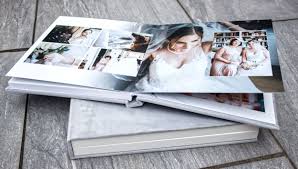 two gray covered wedding albums.  One stacked on top of the other.  The one on top is open showing photos from a wedding day. 