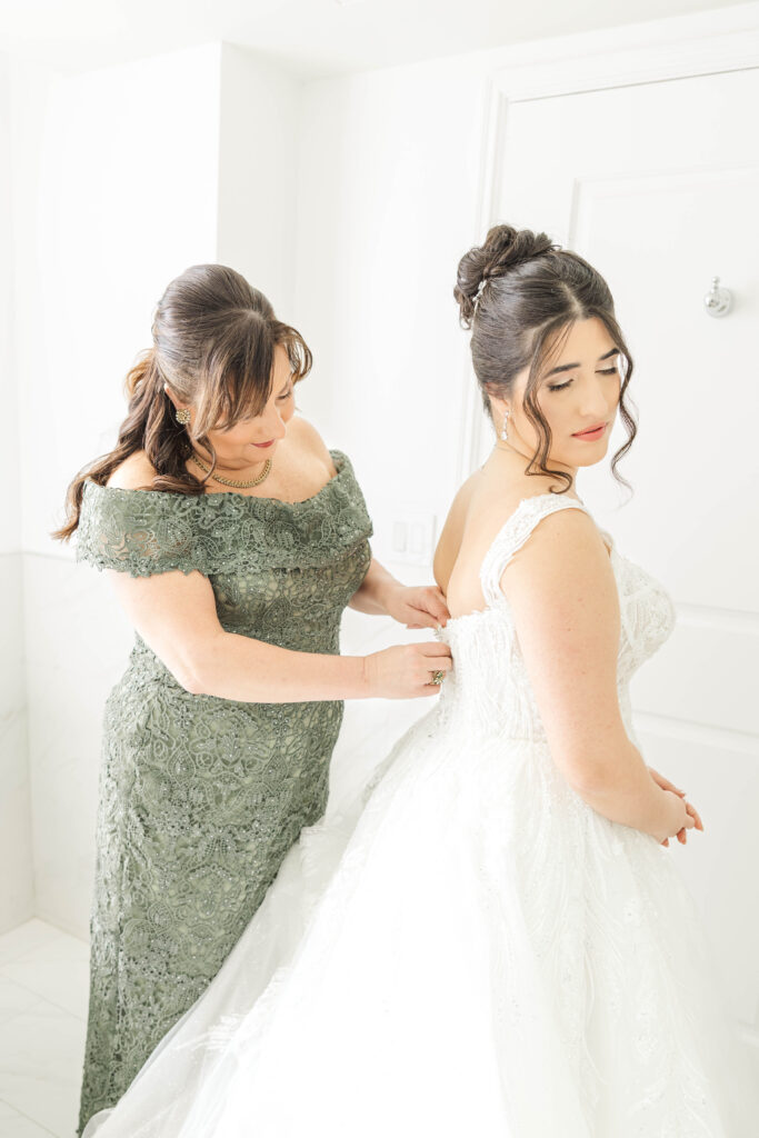 Mother of the bride helping her daughter into her wedding dress, a tender moment captured at The Virginia Cavalier.