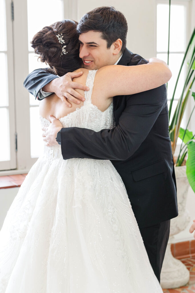 Bride sharing a heartfelt smile with a loved one, holding hands in a sunlit room with elegant decor and natural light at The Virginia Cavalier